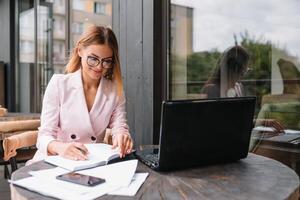 Portrait of young attractive businesswoman examining paperwork in bight light office interior sitting next to the window, business woman read some documents before meeting, filtered image. photo