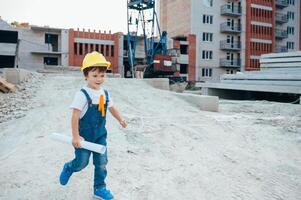 Architect in helmet writing something near new building. little cute boy on the building as an architect photo