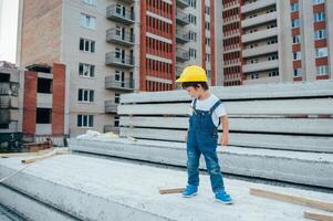 arquitecto en casco escritura alguna cosa cerca nuevo edificio. pequeño linda chico en el edificio como un arquitecto. foto