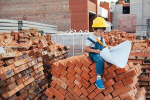 Architect in helmet writing something near new building. little cute boy on the building as an architect. photo