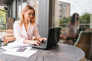 Portrait of young attractive businesswoman examining paperwork in bight light office interior sitting next to the window, business woman read some documents before meeting, filtered image. photo