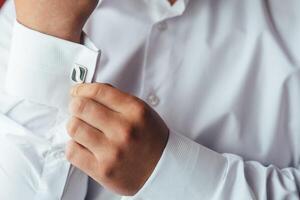 masculino manos en un antecedentes de un blanco camisa, manga camisa con gemelos y relojes, fotografiado de cerca. foto