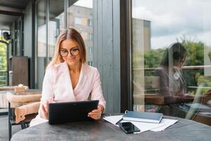 Portrait of young attractive businesswoman examining paperwork in bight light office interior sitting next to the window, business woman read some documents before meeting, filtered image photo