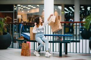 minorista, gesto y rebaja concepto - sonriente Adolescente niña con muchos compras pantalones a centro comercial foto