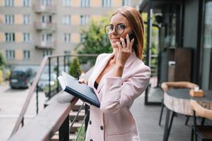 Portrait of young attractive businesswoman examining paperwork in bight light office interior sitting next to the window, business woman read some documents before meeting, filtered image. photo