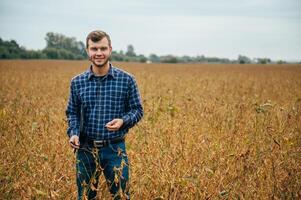 Agronomist holds tablet touch pad computer in the soy field and examining crops before harvesting. Agribusiness concept. agricultural engineer standing in a soy field with a tablet. photo