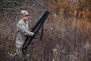 un masculino cazador con un pistola mientras sentado toma objetivo a un bosque. el concepto de un exitoso caza, un experimentado cazador. caza el otoño estación. el cazador tiene un rifle y un caza uniforme foto