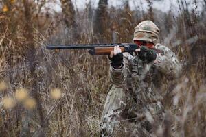 un masculino cazador con un pistola mientras sentado toma objetivo a un bosque. el concepto de un exitoso caza, un experimentado cazador. caza el otoño estación. el cazador tiene un rifle y un caza uniforme foto