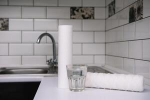 agua filtros carbón cartuchos y un vaso en un blanco cocina antecedentes. casa filtración sistema foto