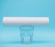 Water filters. Carbon cartridges and a glass with water on a blue background. Household filtration system photo