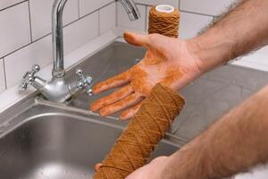 Hand holding dirty water filter cartridge over the sink. Brown coloring. Evidence of contamination of tap water with iron cations photo