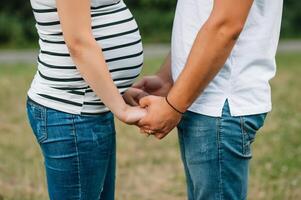 imagen de embarazada Pareja. marido conmovedor su esposa barriga con manos. embarazada mujer al aire libre. foto