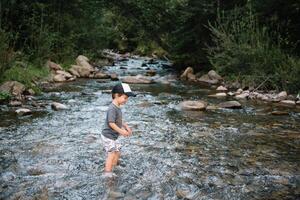 happy boy on a walk near the river in the mountains photo