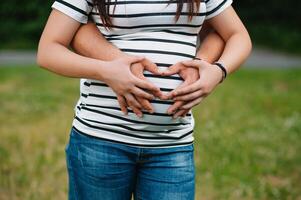 imagen de embarazada Pareja. marido conmovedor su esposa barriga con manos. embarazada mujer al aire libre. foto