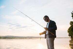 Young man fishing at misty sunrise photo