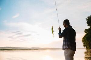 Young man fishing at misty sunrise. photo