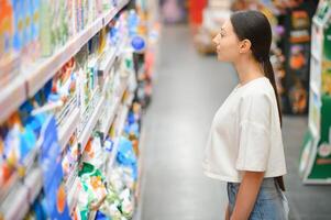 un joven mujer elige casa productos quimicos en un supermercado. medio para Lavado y limpieza el casa foto