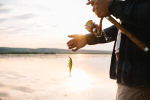 el del pescador manos, sostiene el hilado vara, gira el bobina manejar. pasatiempo y actividad. foto