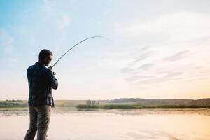 Fishing. spinning at sunset. Silhouette of a fisherman. photo