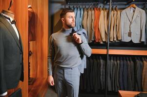 Modern young handsome businessman, looking and choosing classical suit in the suit shop photo