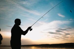 Fishing. spinning at sunset. Silhouette of a fisherman photo