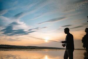 Fishing. spinning at sunset. Silhouette of a fisherman photo