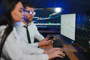 Team of stockbrokers are having a conversation in a dark office with display screens photo