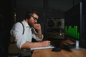 A male spy listens and records conversations on a reel-to-reel tape recorder photo