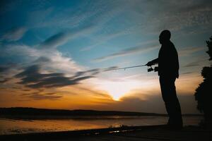 Fishing. spinning at sunset. Silhouette of a fisherman. photo