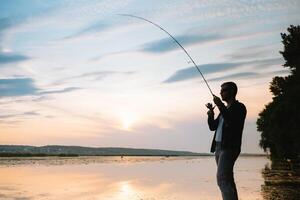 Young man fishing at misty sunrise photo