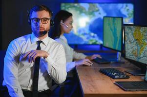 Center of dispatching maintenance. Portrait of cheerful woman and man working via headset microphone while sitting on navigation controller board photo