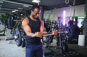 atlético negro chico haciendo levantamiento de pesas o levantamiento de pesas a moderno gimnasio foto