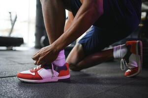 Sportsman tying shoelaces, ready for workout in gym, free space photo