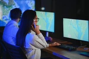 Center of dispatching maintenance. Portrait of cheerful woman and man working via headset microphone while sitting on navigation controller board photo