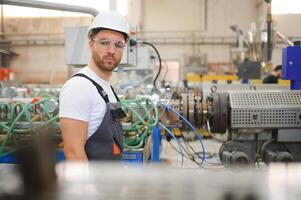 sonriente y contento empleado. industrial trabajador adentro en fábrica. joven técnico con difícil sombrero foto