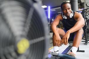 motivado joven negro deportista teniendo rutina de ejercicio en remo máquina foto