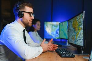 Center of dispatching maintenance. Portrait of cheerful woman and man working via headset microphone while sitting on navigation controller board photo