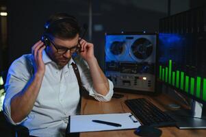 A male spy listens and records conversations on a reel-to-reel tape recorder photo