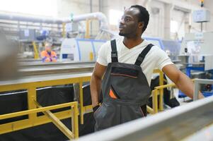 africano masculino ingeniero. controlar un material producción máquina sistema, trabajando en un el plastico y acero industria con respecto a el de la empresa producto negocio. foto