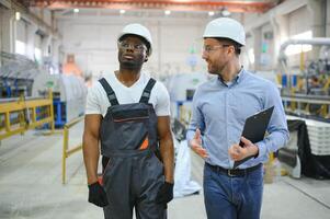 dos trabajadores en producción planta como equipo que se discute, industrial escena en antecedentes foto