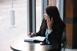 mujer de negocios hablando en el teléfono y tomando notas foto