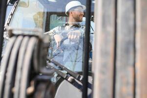Portrait of heavy industry forklift driver giving thumbs up and smiling photo