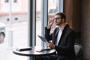 un hombre sentado en un café con tableta. casual hombre utilizando tableta computadora sentado en café surf Internet foto