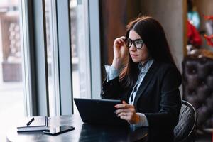 contento joven mujer de negocios utilizando tableta computadora en un cafetería. selectivo atención foto