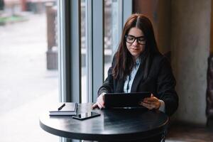 Happy young businesswoman using tablet computer in a cafe. Selective focus photo