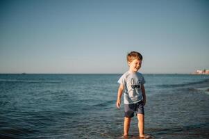 linda pequeño chico corriendo en playa y tener divertida. foto