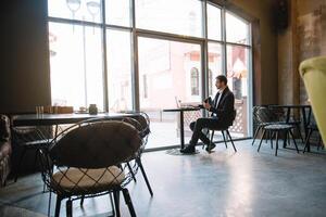 Young successful businessman working on a laptop while sitting in cafe photo