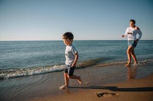 madre y hijo jugando en el playa a el puesta de sol tiempo. concepto de simpático familia. foto