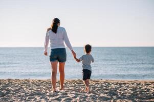 Mother and son playing on the beach at the sunset time. Concept of friendly family photo