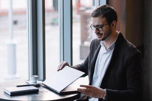 joven exitoso empresario trabajando en un ordenador portátil mientras sentado en café foto